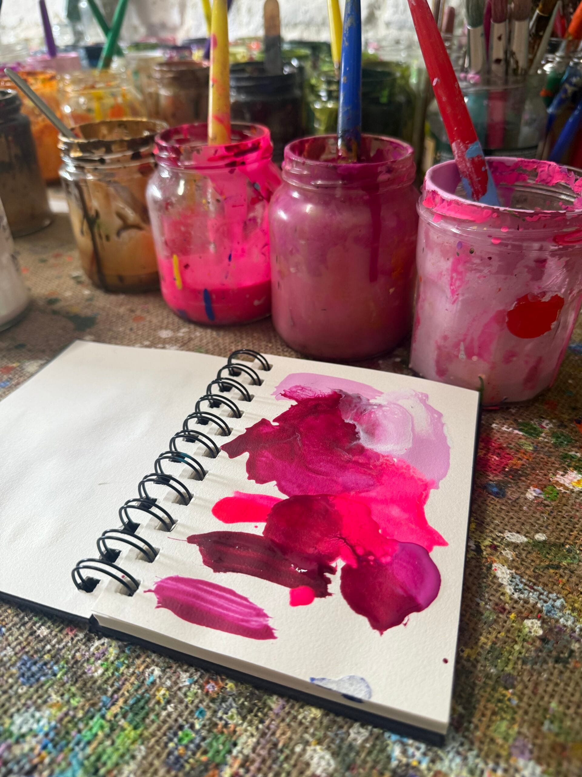 Creating Pink Champagne Blossom Artist’s sketchbook and pink acrylic paints during the creation of Pink Champagne Blossom by Sally Oasis