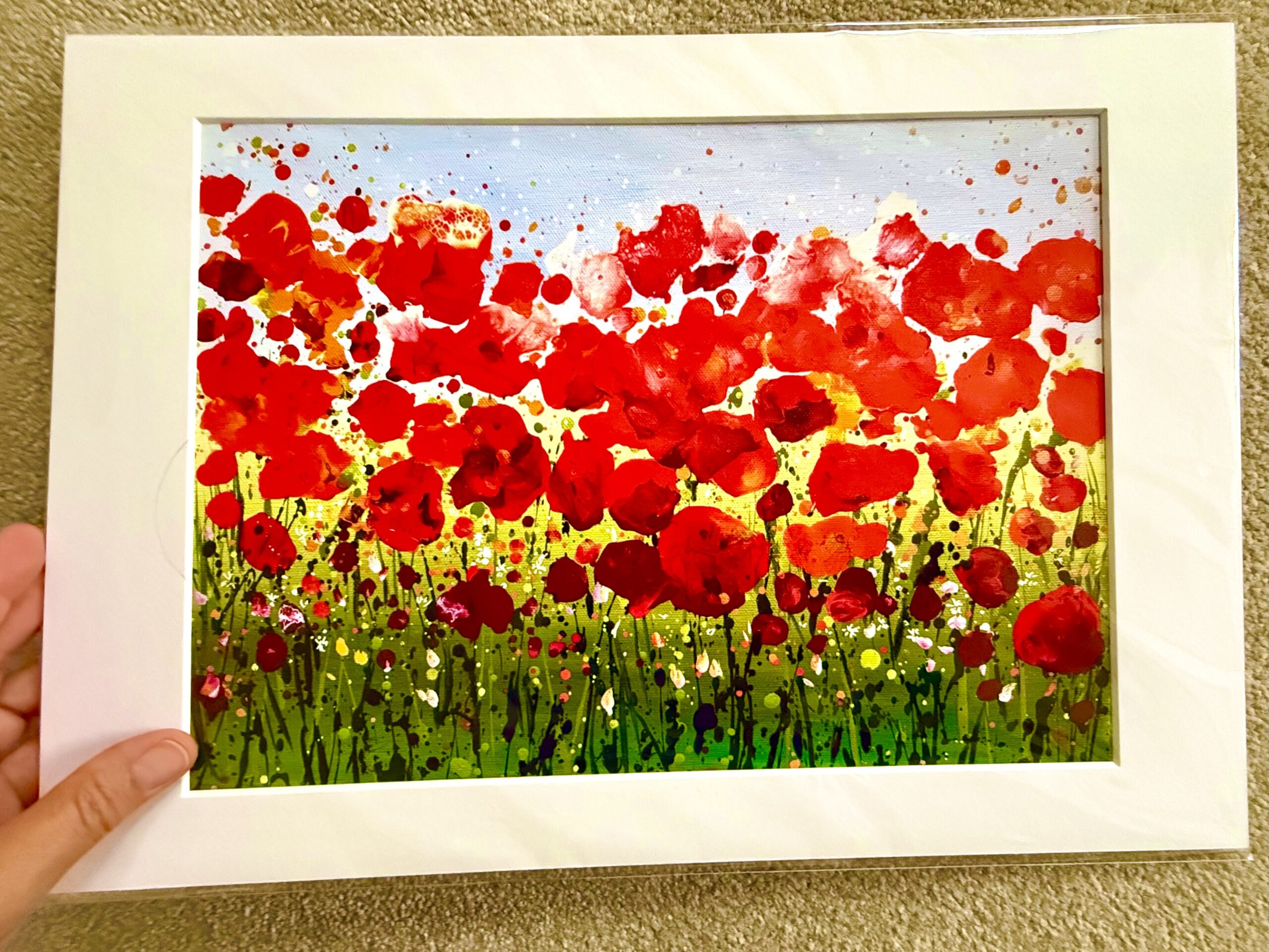 Ruby Days | A3 Mounted Print Held for Scale A hand holding the Ruby Days A3 mounted print, showing its white mount around a colourful red poppy meadow scene.