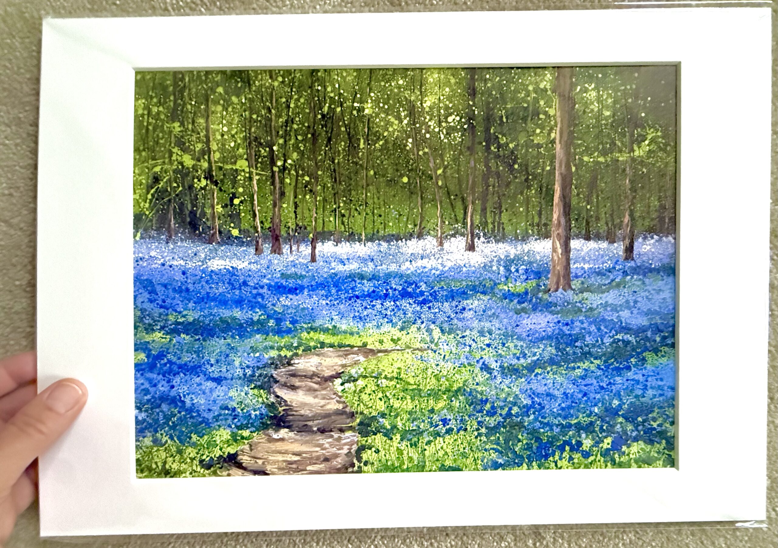 Spring Bluebells | A3 Bluebell Woodland Art Print Spring Bluebells A3 mounted print by Sally Oasis, showing a winding woodland path through vivid bluebells beneath tall trees and fresh green foliage.